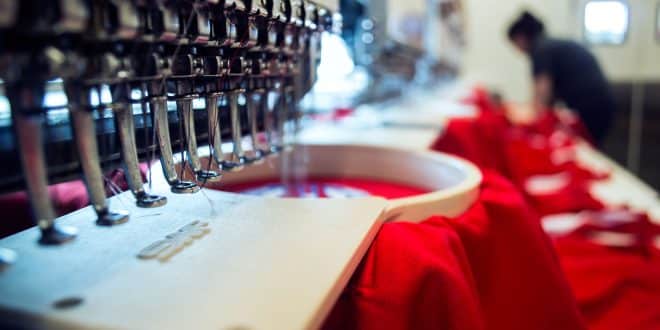 A red shirt is being embroidered on a machine.