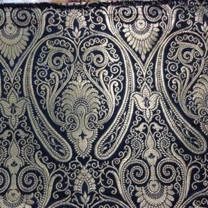 A black and gold paisley fabric on a table.