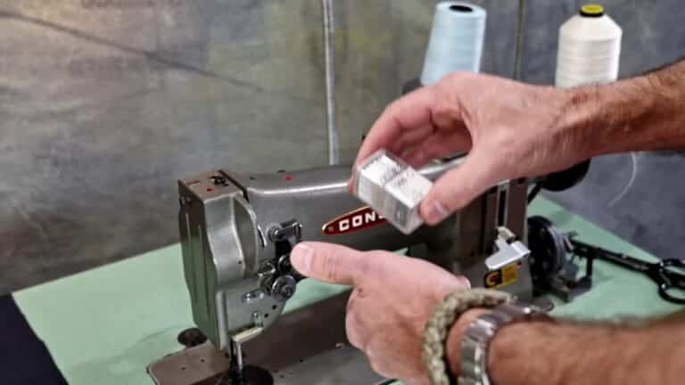 A man is using a sewing machine to sew a piece of fabric, while providing a review on the Consew CN897VF-1.