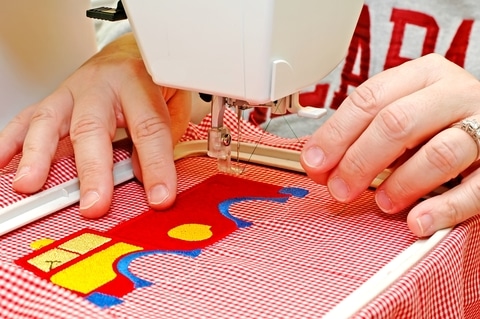 woman sitting at an embroidery machine Seamsecrets