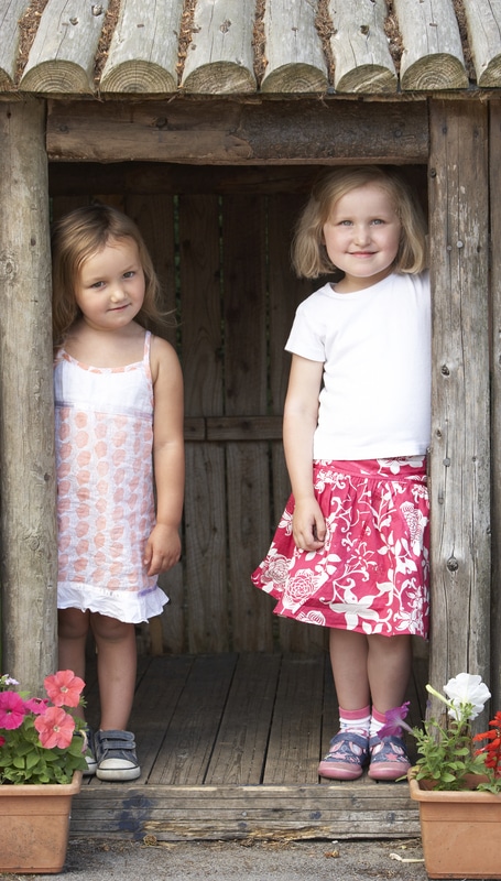 Two girls stitching a vibrant quilting tale in a wooden shed.